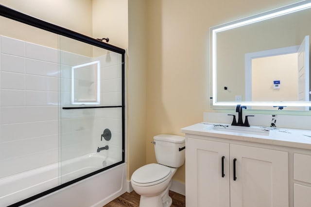 full bathroom with vanity, combined bath / shower with glass door, wood-type flooring, and toilet