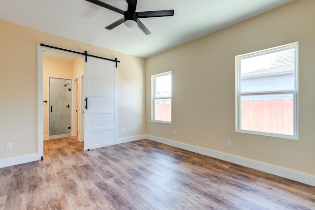 interior space with light hardwood / wood-style floors, a barn door, and ceiling fan