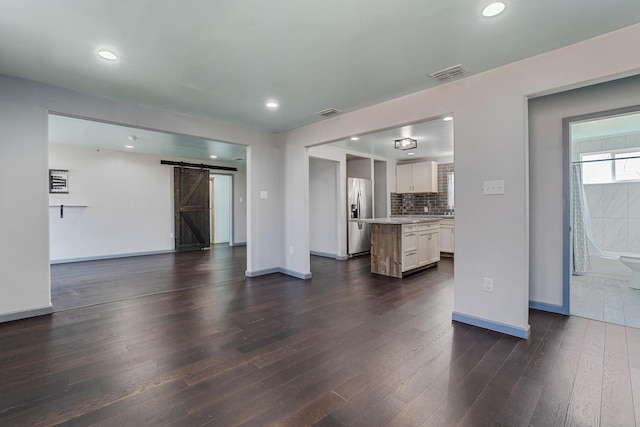 living room with a barn door and dark wood-type flooring