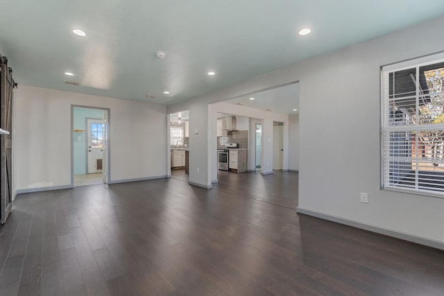 unfurnished living room featuring a barn door and dark hardwood / wood-style flooring