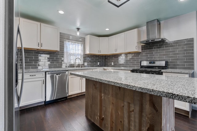 kitchen featuring light stone counters, appliances with stainless steel finishes, wall chimney exhaust hood, and white cabinets