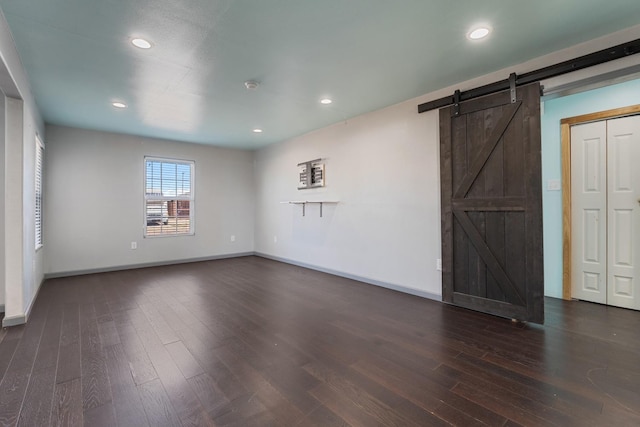 spare room featuring dark hardwood / wood-style floors and a barn door