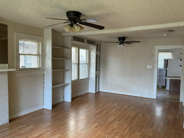 unfurnished living room with ceiling fan, hardwood / wood-style floors, and a textured ceiling