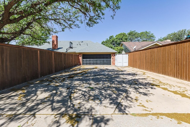 9613 Vicksburg Ave, Lubbock, TX 79424 - view of side of property with concrete driveway, an attached garage, and a chimney