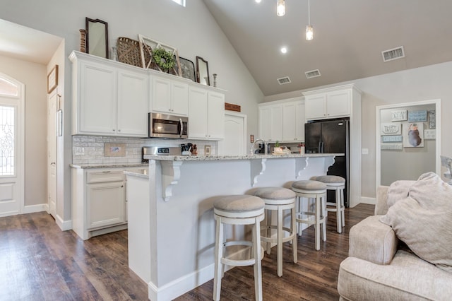 4902 Marshall St, Lubbock, TX 79416 - kitchen featuring appliances with stainless steel finishes, white cabinets, dark wood finished floors, and high vaulted ceiling