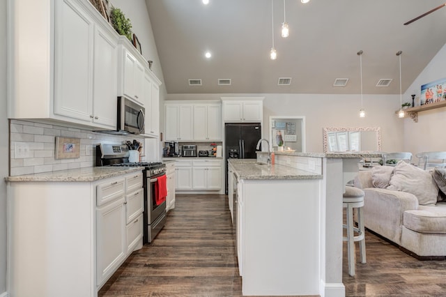 4902 Marshall St, Lubbock, TX 79416 - kitchen with appliances with stainless steel finishes, a breakfast bar, open floor plan, tasteful backsplash, and white cabinets