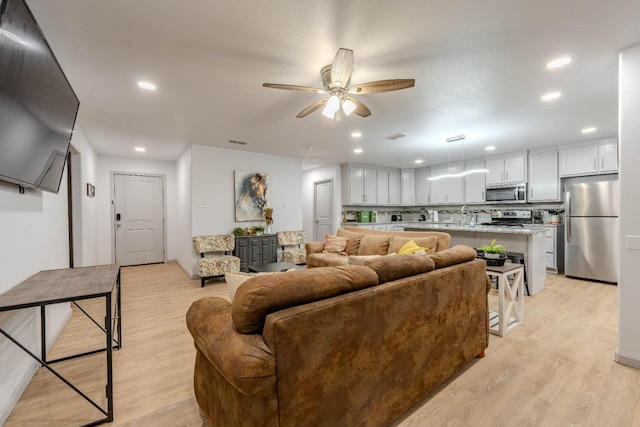 living room featuring ceiling fan, sink, and light hardwood / wood-style floors