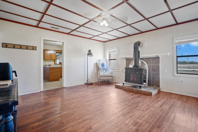 unfurnished living room with hardwood / wood-style flooring, coffered ceiling, and a wood stove