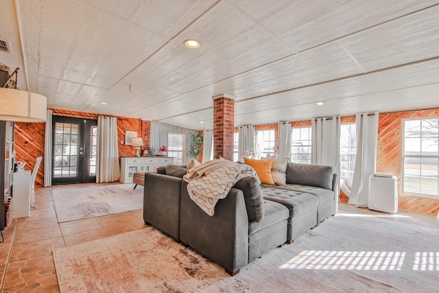 living room with french doors, recessed lighting, a wealth of natural light, and wooden walls