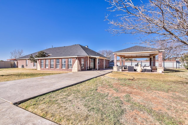 exterior space featuring brick siding, a yard, a patio, a gazebo, and fence