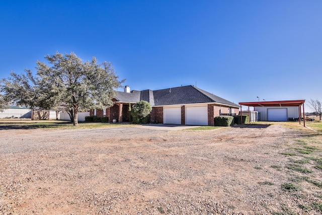 ranch-style house featuring dirt driveway, brick siding, and a garage