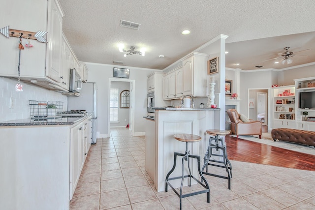 kitchen featuring a breakfast bar area, stainless steel appliances, visible vents, open floor plan, and light tile patterned flooring