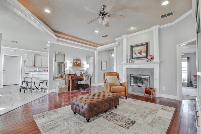 living room featuring visible vents, hardwood / wood-style floors, and a tile fireplace