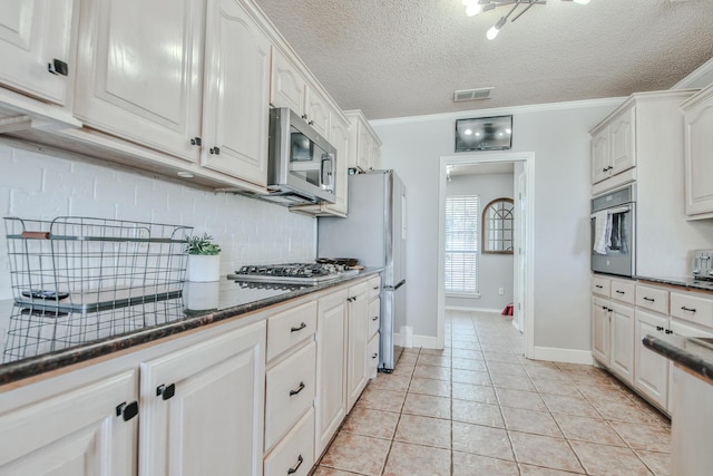 kitchen with visible vents, white cabinets, decorative backsplash, stainless steel appliances, and light tile patterned flooring