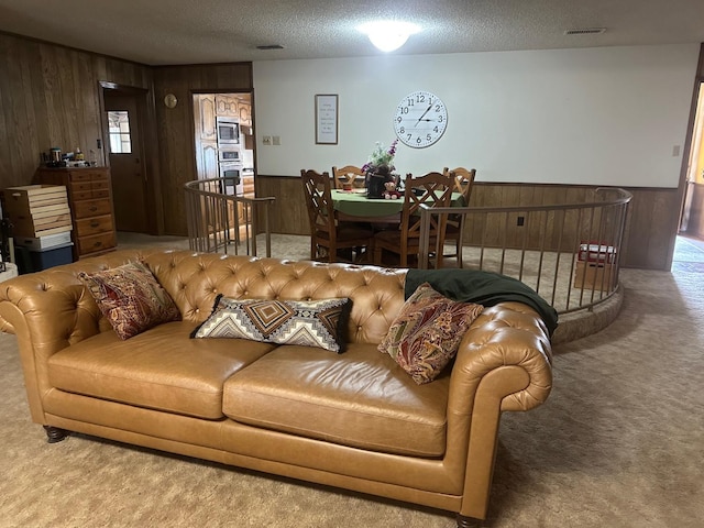 living room featuring carpet floors, wooden walls, and a textured ceiling