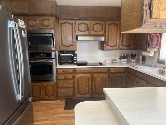 kitchen featuring appliances with stainless steel finishes, sink, a textured ceiling, and light hardwood / wood-style flooring