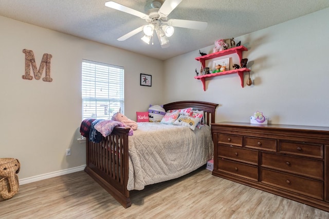 bedroom with ceiling fan, light hardwood / wood-style floors, and a textured ceiling