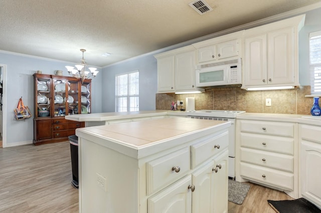 kitchen featuring crown molding, decorative light fixtures, a center island, white appliances, and decorative backsplash