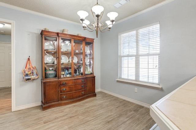 dining area featuring crown molding, a chandelier, and light hardwood / wood-style flooring