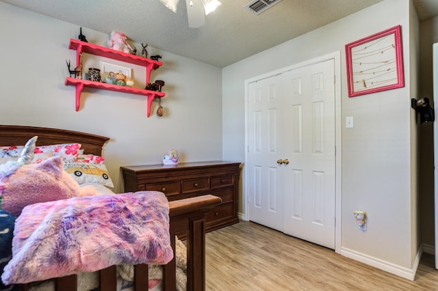 bedroom with a textured ceiling, light hardwood / wood-style floors, and ceiling fan