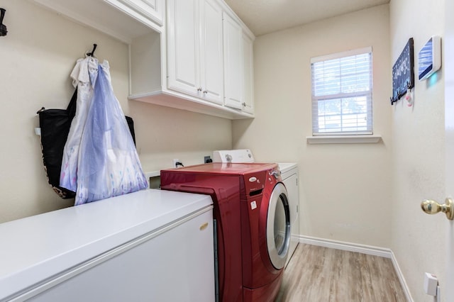 washroom with light hardwood / wood-style floors, washing machine and dryer, and cabinets