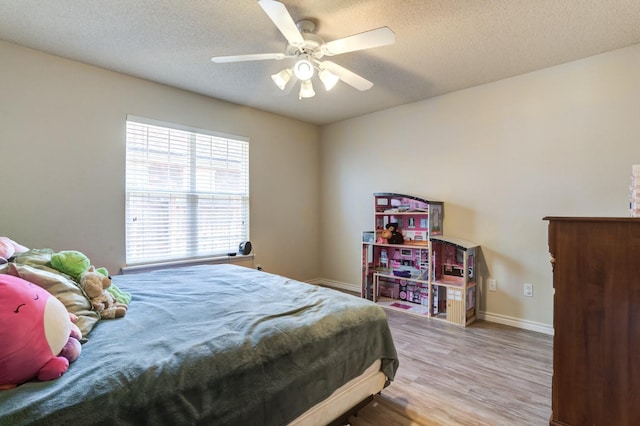 bedroom featuring ceiling fan, wood-type flooring, and a textured ceiling