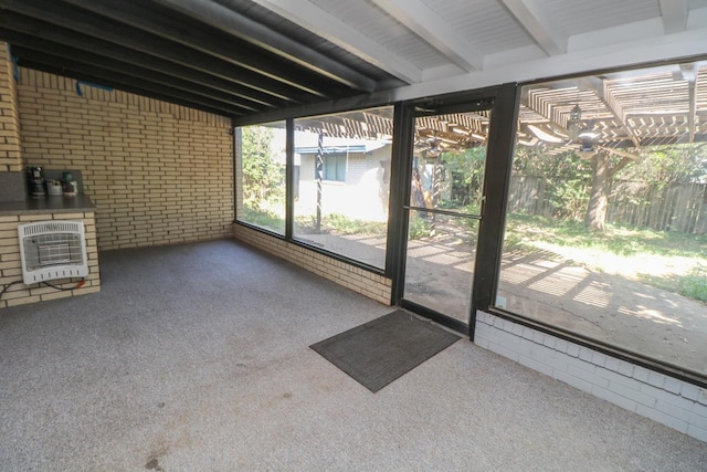 unfurnished sunroom featuring heating unit and beam ceiling