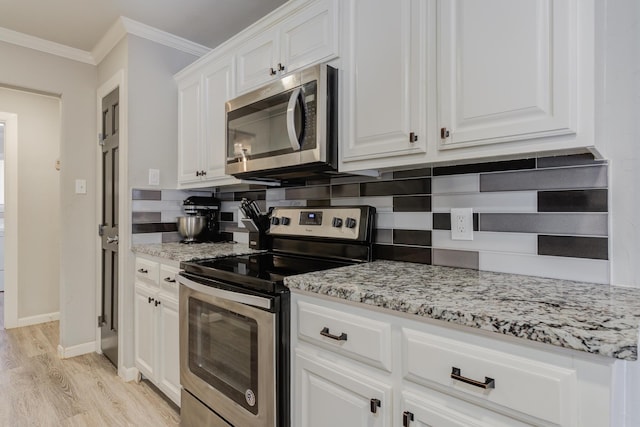 kitchen with light stone countertops, stainless steel appliances, white cabinets, ornamental molding, and light wood finished floors