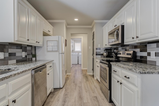 kitchen with light wood-style flooring, washer and dryer, stainless steel appliances, white cabinets, and backsplash