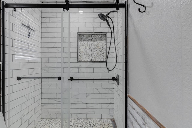 bathroom featuring a textured wall and a stall shower