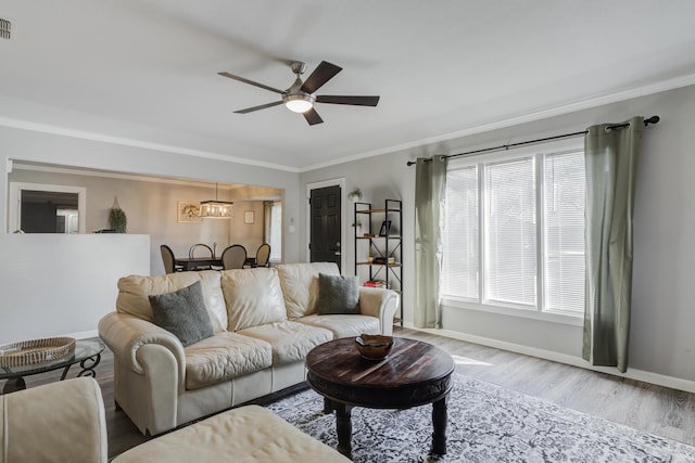 living area featuring wood finished floors, ceiling fan, baseboards, visible vents, and crown molding
