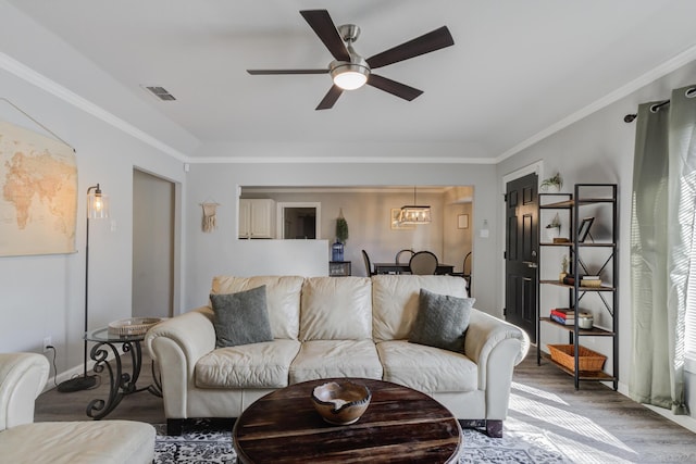 living room featuring wood finished floors, visible vents, a ceiling fan, and crown molding