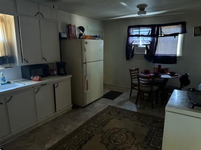 kitchen with white refrigerator, white cabinetry, plenty of natural light, and sink