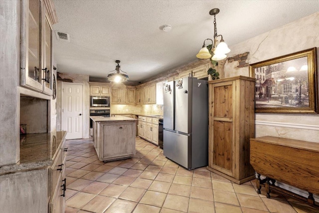 kitchen with a textured ceiling, hanging light fixtures, light brown cabinets, appliances with stainless steel finishes, and a kitchen island