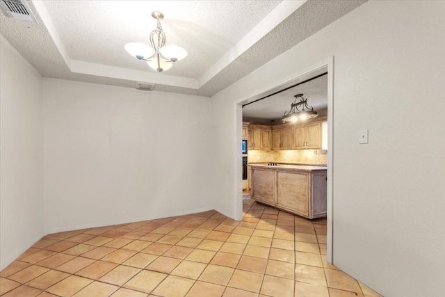 unfurnished dining area with an inviting chandelier, a tray ceiling, light tile patterned flooring, and a textured ceiling