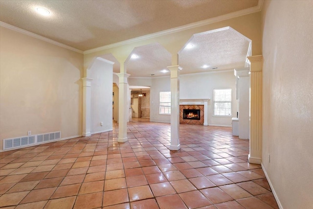 unfurnished living room with a textured ceiling, light tile patterned floors, ornamental molding, a premium fireplace, and decorative columns