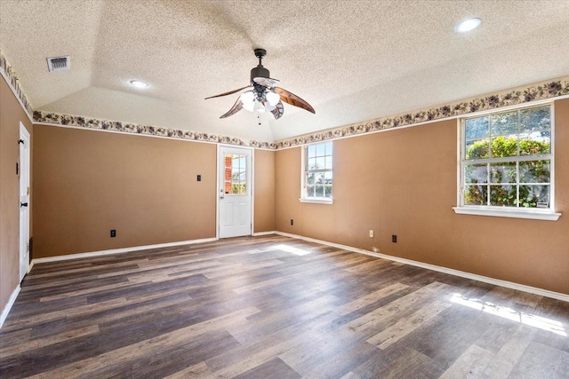 spare room featuring dark wood-type flooring, ceiling fan, lofted ceiling, and a textured ceiling