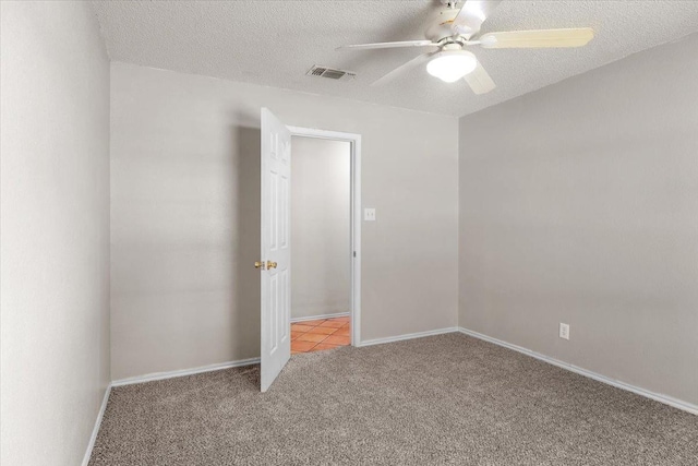 carpeted empty room featuring ceiling fan and a textured ceiling