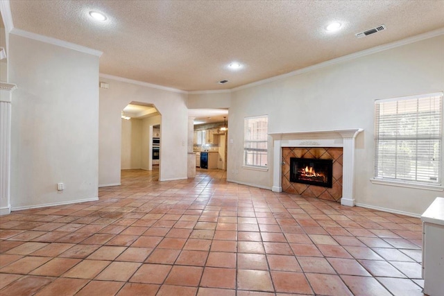 unfurnished living room with light tile patterned flooring, ornamental molding, a wealth of natural light, and a fireplace