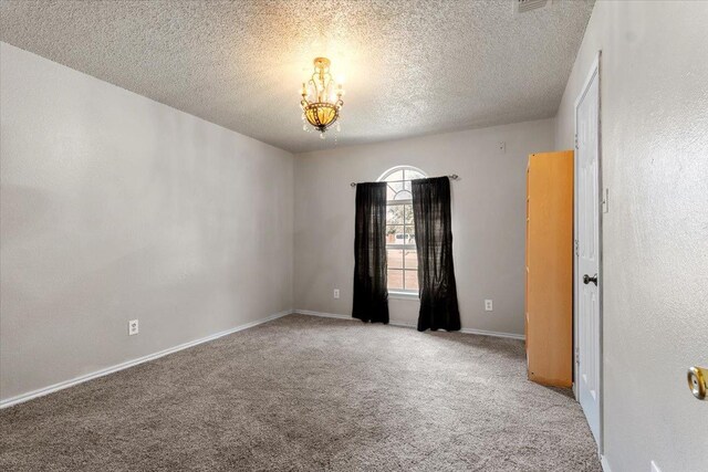 spare room with light carpet, a notable chandelier, and a textured ceiling