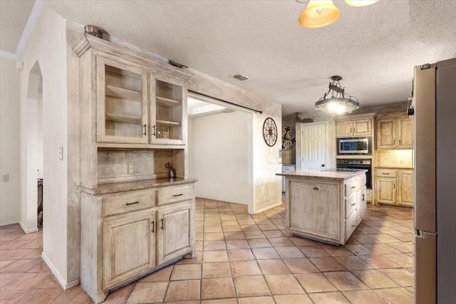 kitchen featuring pendant lighting, appliances with stainless steel finishes, a textured ceiling, and a kitchen island