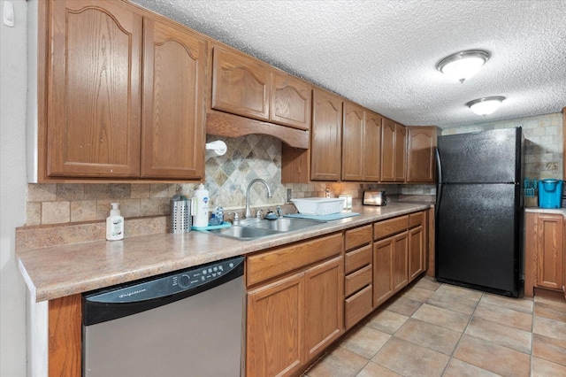 kitchen with black fridge, stainless steel dishwasher, sink, and decorative backsplash