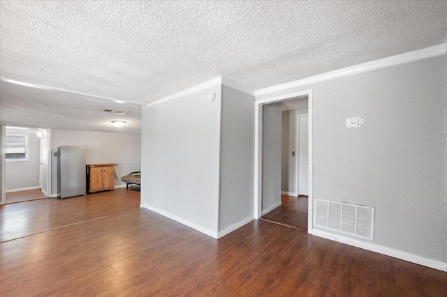 unfurnished room with ornamental molding, dark wood-type flooring, and a textured ceiling