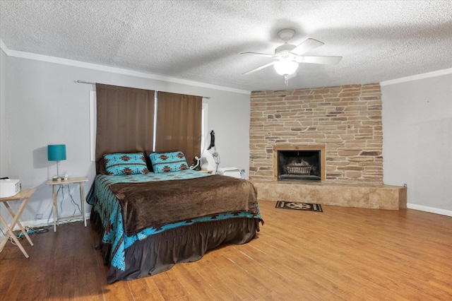 bedroom featuring crown molding, wood-type flooring, a textured ceiling, and a fireplace