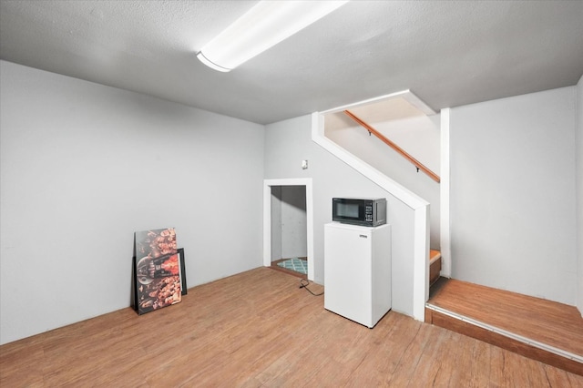 bonus room with a textured ceiling and light hardwood / wood-style flooring