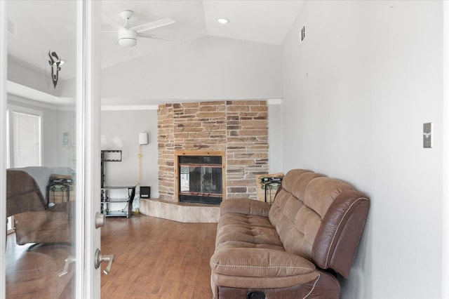 living room featuring hardwood / wood-style floors, a stone fireplace, vaulted ceiling, and ceiling fan