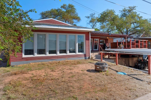 rear view of house with a fire pit and a lawn