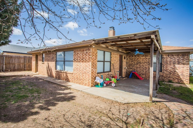 rear view of property featuring ceiling fan, a patio, fence, brick siding, and a chimney