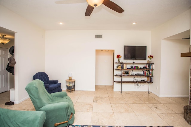 living area featuring light tile patterned floors, visible vents, baseboards, and a ceiling fan