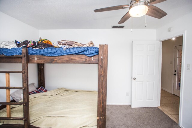 carpeted bedroom with a ceiling fan and visible vents